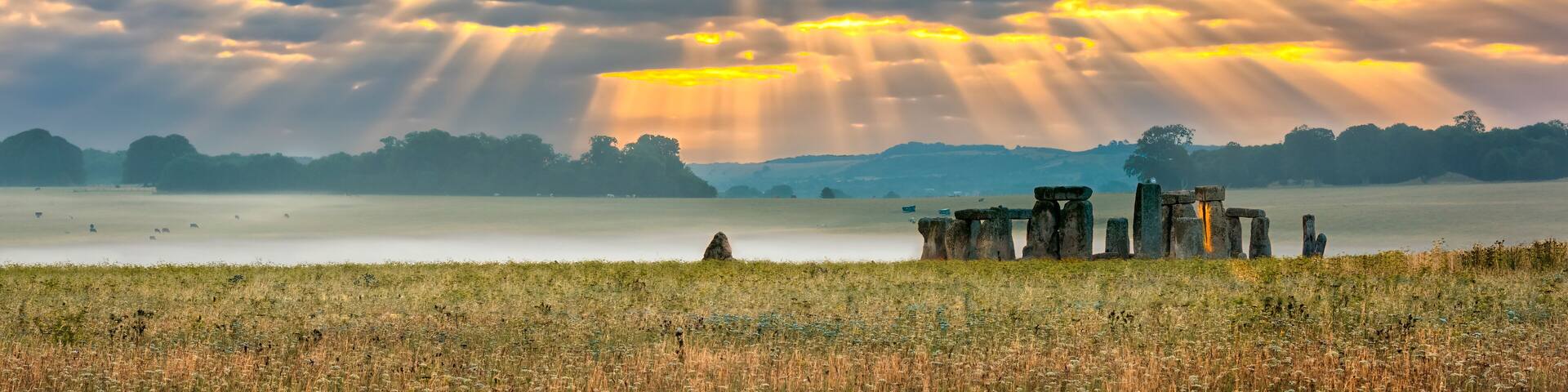 Amesbury, Wiltshire, United Kingdom - August 14, 2016: Cloudy sunrise over Stonehenge - prehistoric megalith monument arranged in circle.