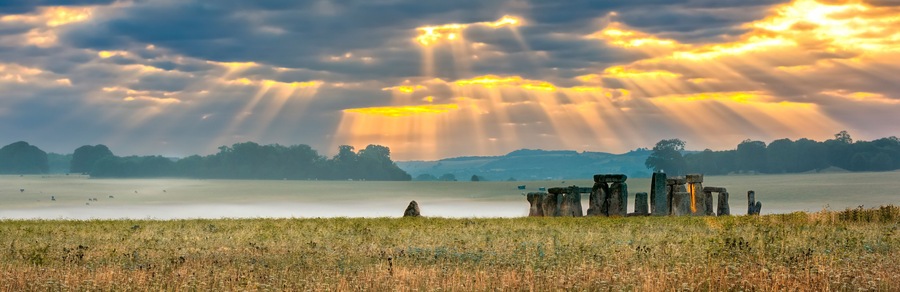 Amesbury, Wiltshire, United Kingdom - August 14, 2016: Cloudy sunrise over Stonehenge - prehistoric megalith monument arranged in circle.