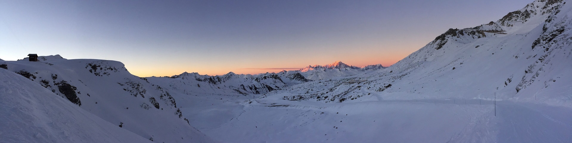 A snow-covered mountain range at sunset with a clear sky.