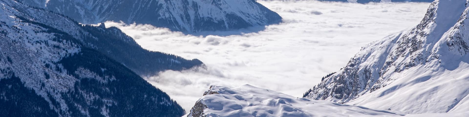 Red gondola of cable car seen from Bellecote glacier, La Plagne ski resort, France, in winter. Inversion clouds in valley