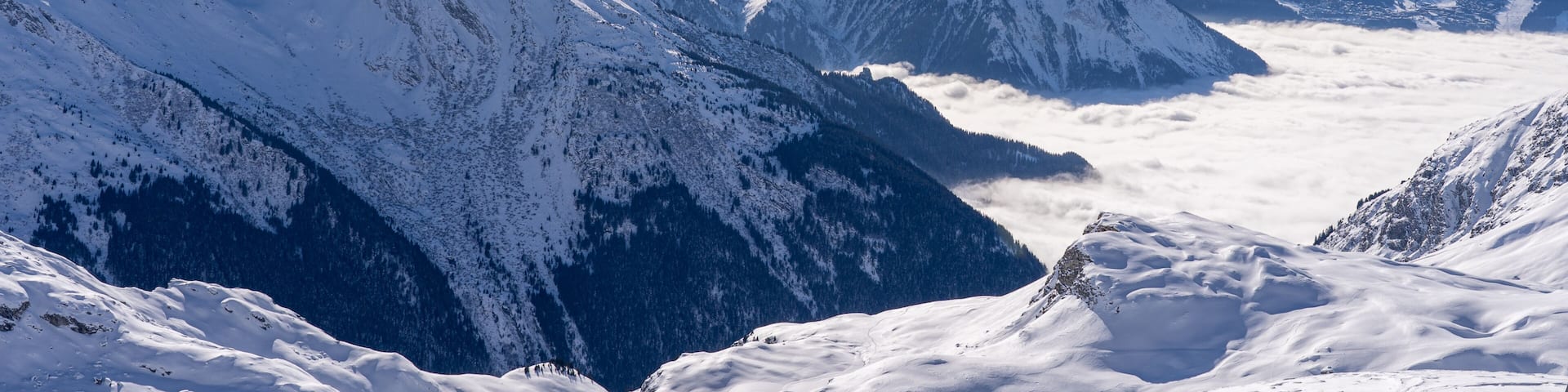 Red gondola of cable car seen from Bellecote glacier, La Plagne ski resort, France, in winter. Inversion clouds in valley