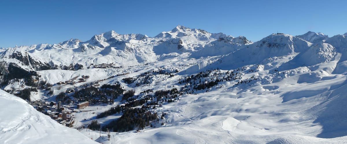 A snow-covered mountain range with ski slopes and a small town nestled in the valley.
