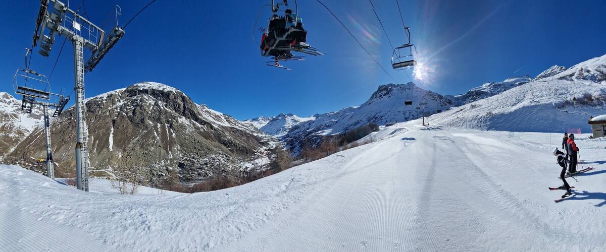 A ski lift, snow-covered mountains, and a ski slope.