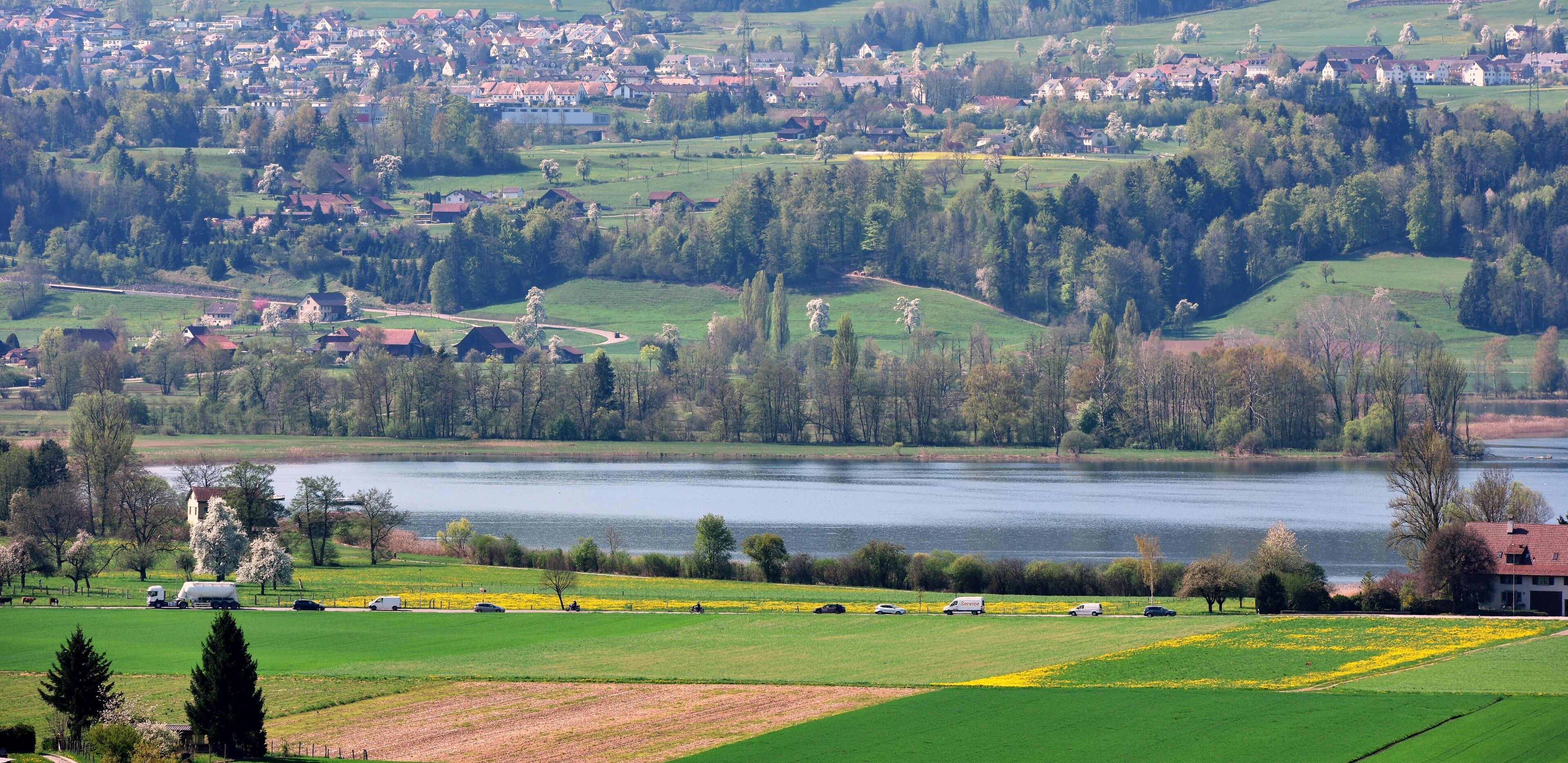 A lakeside town with green fields, a church, and a river.