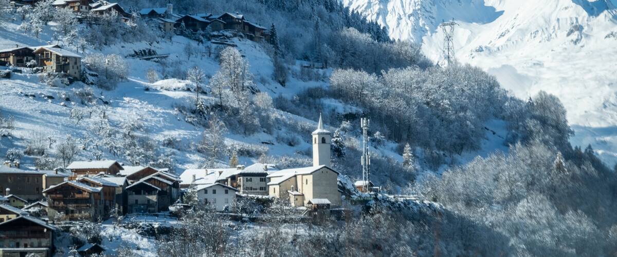 A snow-covered mountain village with wooden houses and a church.