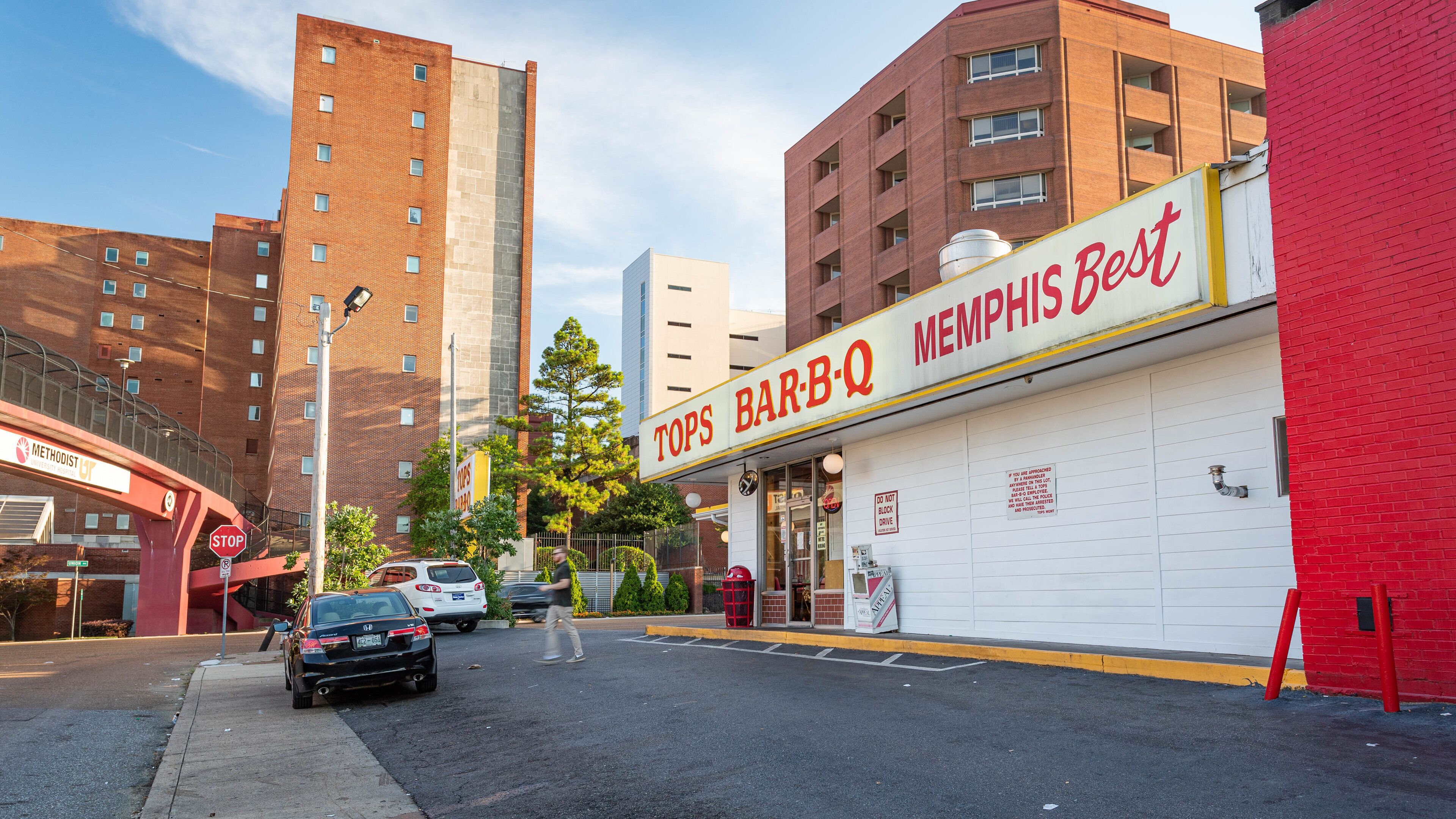 A street with a red building labeled "TOPS BAR-B-Q" and a white building with a sign "MEMPHIS BEST".