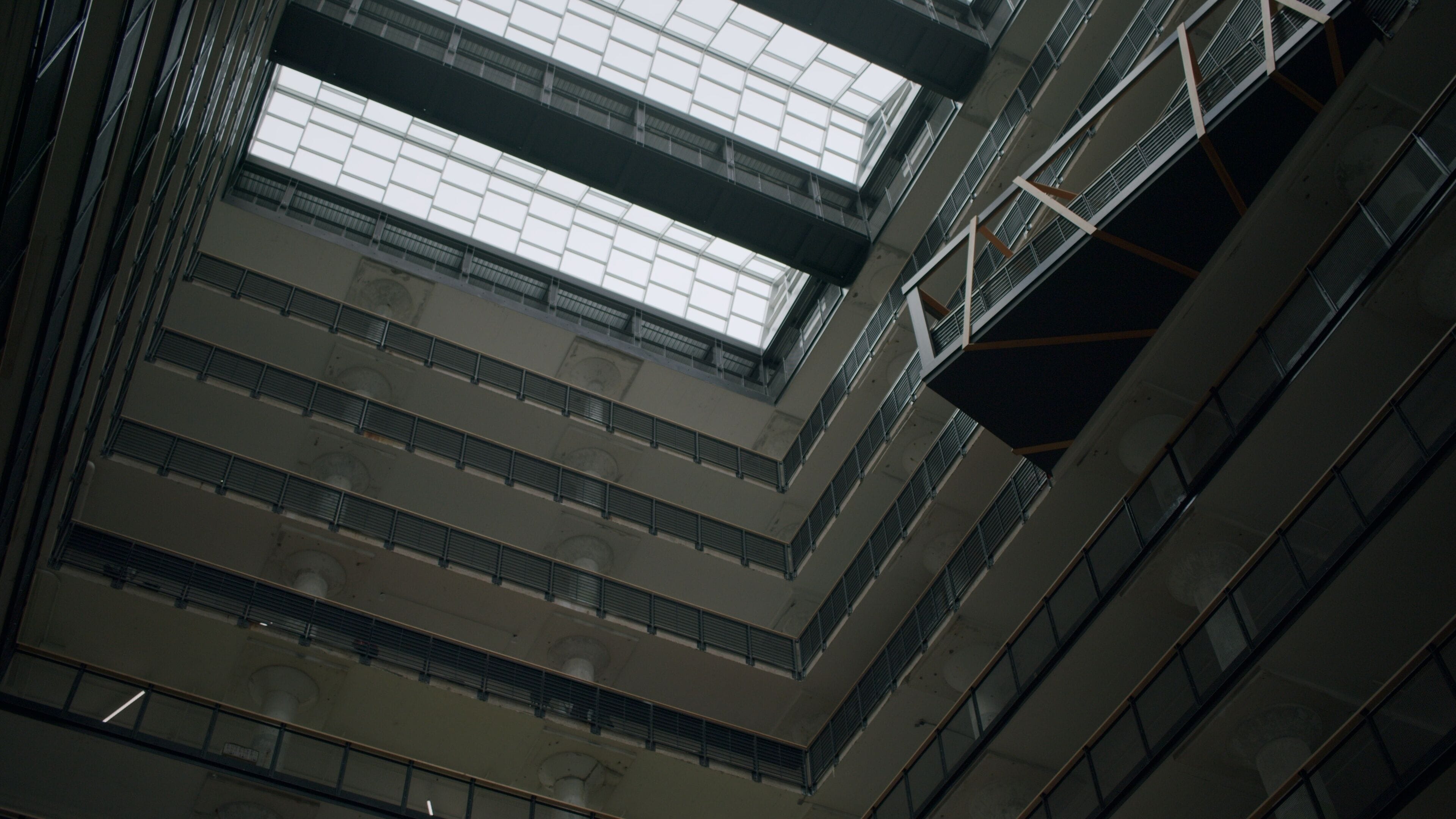 Ein mehrgeschossiges Atrium mit Glasdecke und Metallgeländern.