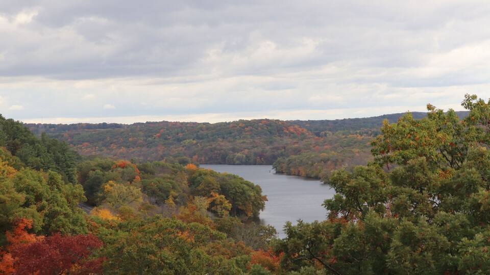 A lake surrounded by autumn-colored trees and a cloudy sky.