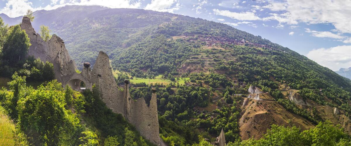 A mountainous landscape with a castle ruin and a village.