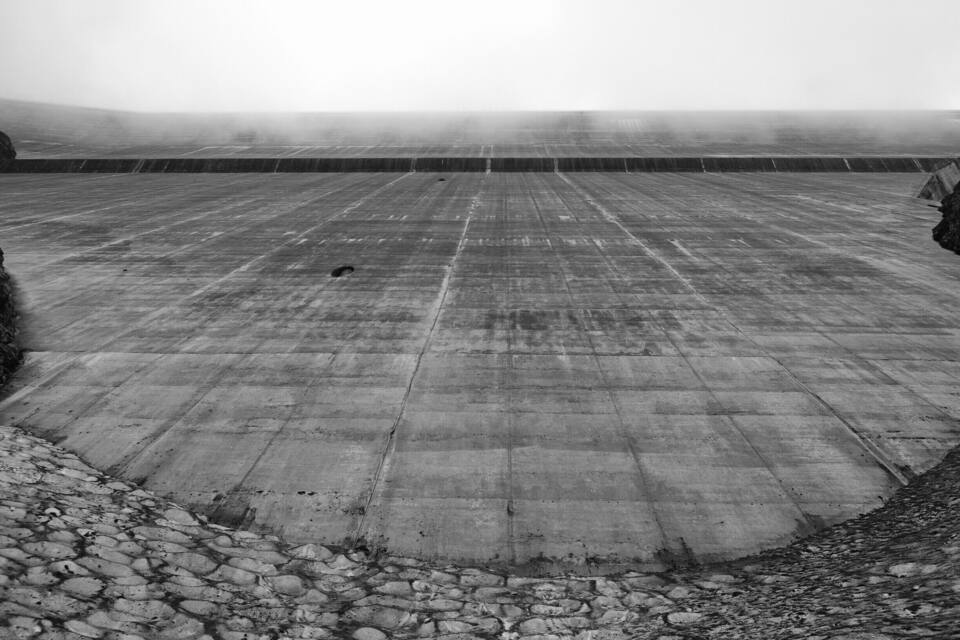 A large concrete structure with a grid pattern, surrounded by a rocky terrain.