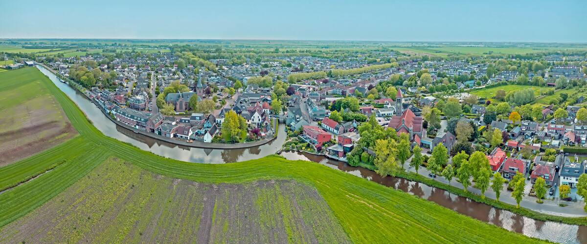 A river winding through a town with historic buildings and green fields.