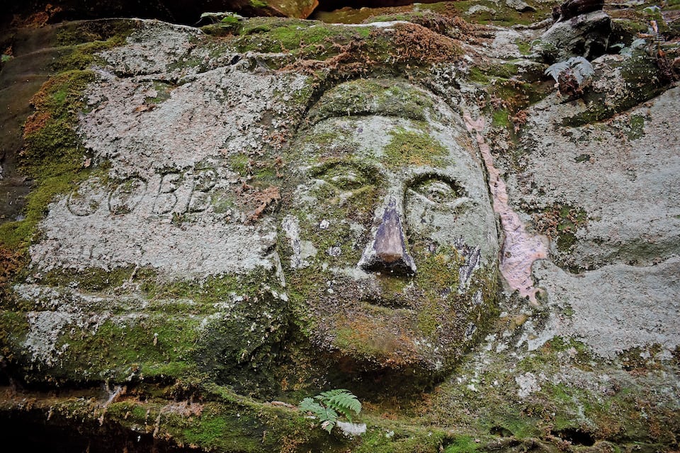 A moss-covered rock with a carved face.