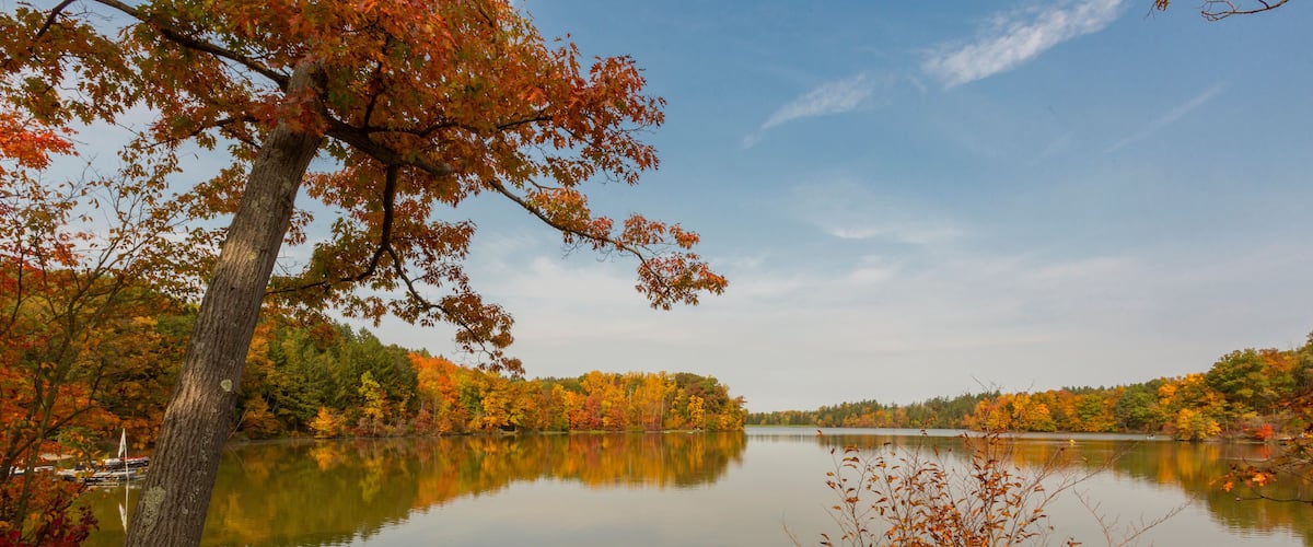 A calm lake surrounded by autumn foliage.