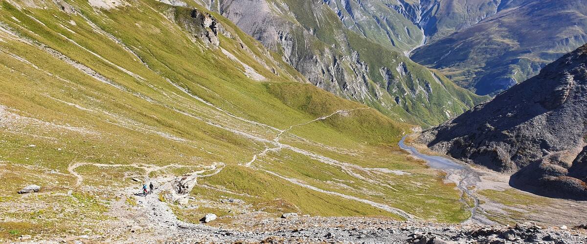 A mountainous landscape with a winding path and a small stream.