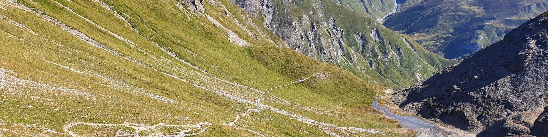 A mountainous landscape with a winding path and a small stream.