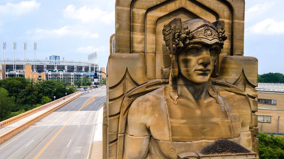 Art Deco "Guardians of Transportation" statue in Cleveland on the Hope Memorial Bridge. Coal car Guardian in foreground showing coal car and Progressive Field in the back.