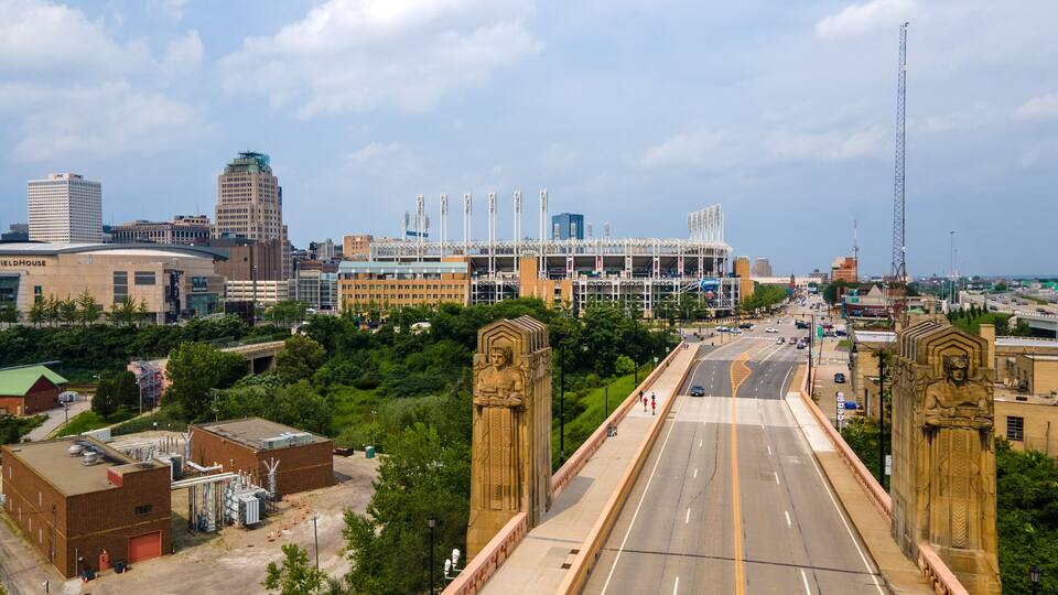 Art Deco "Guardians of Transportation" statue in Cleveland on the Hope Memorial Bridge. Both guardians, and Progressive Field in the background. Industrial buildings near the foreground.