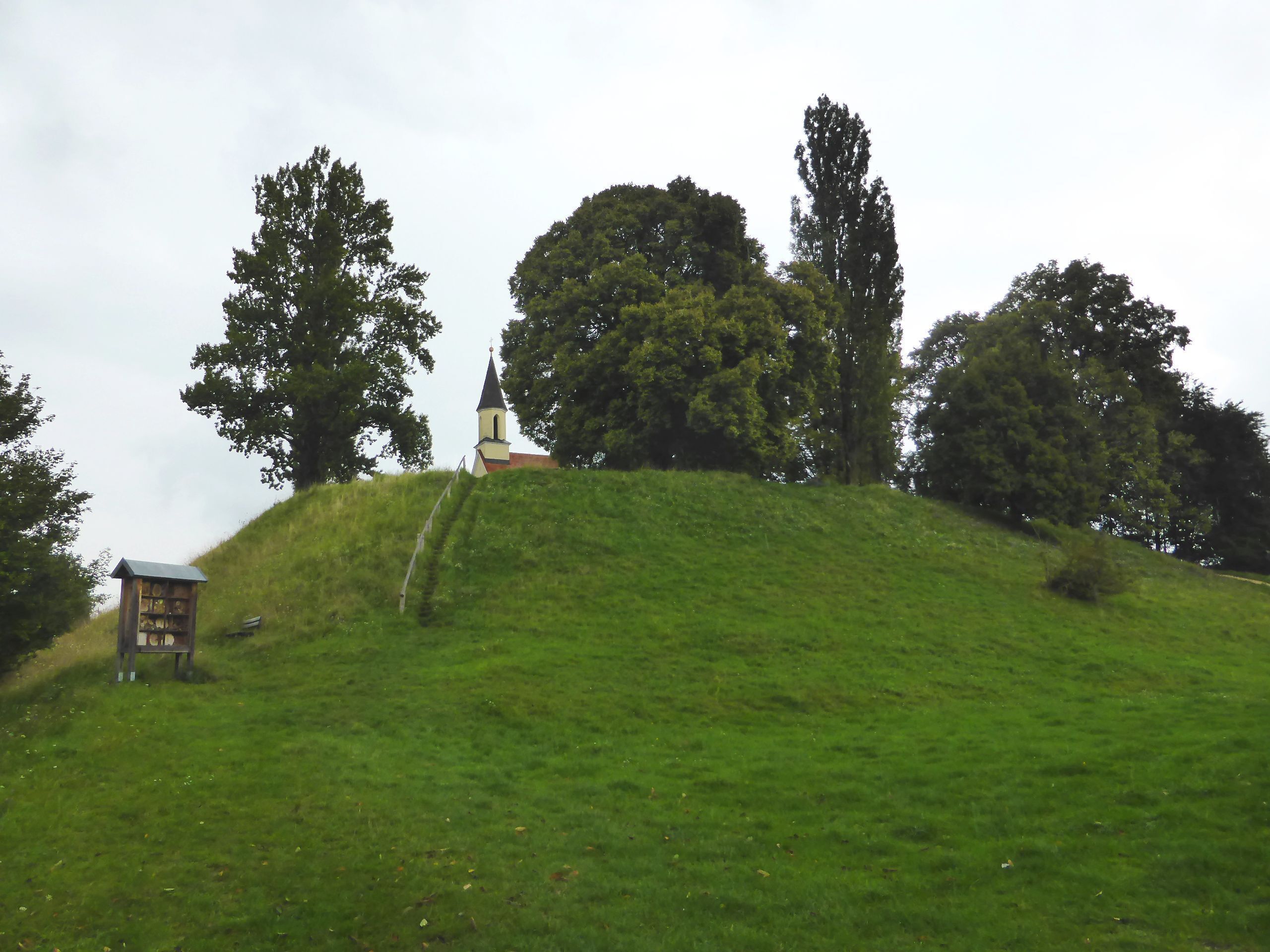 A church on a grassy hill with trees around.
