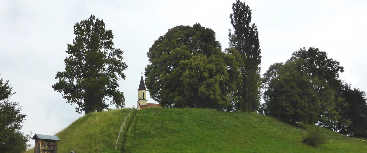 A church on a grassy hill with trees around.