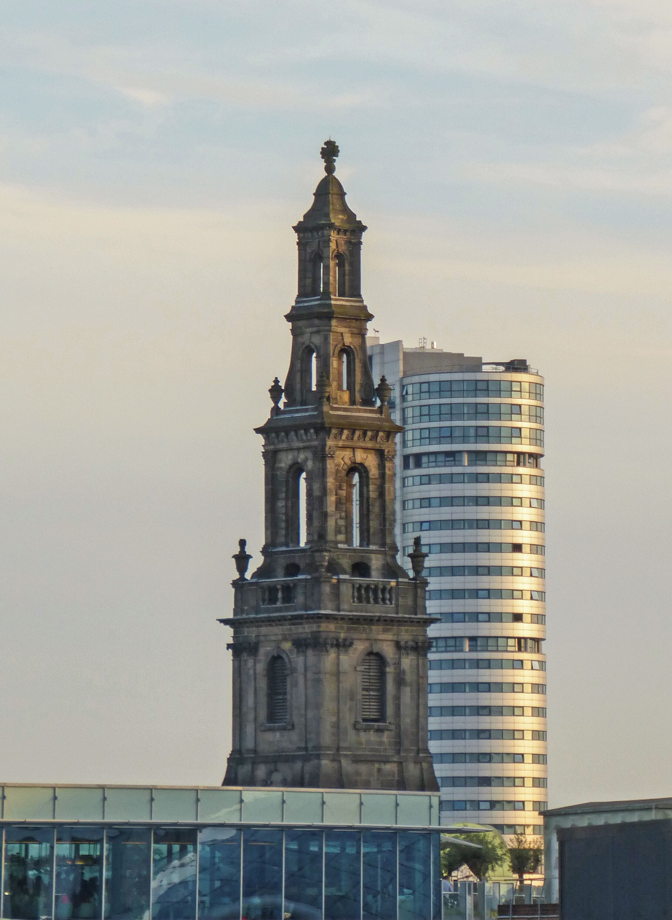 Un beffroi historique, avec un immeuble de grande hauteur moderne en arrière-plan.