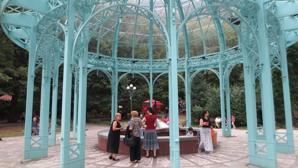 The Borjomi spring in Borjomi, Georgia.
This glass and steel pergola sits over two spigots of the famous Borjomi natural spring water.
Discovered thousands of years ago, but popularized during the Russian imperial period, the mineral waters of Borjomi became renowned for their healing qualities.
Russian figures such as Chekhov and Tchaikovsky visited Borjomi to relax in sanatoriums and drink the water. During the Soviet period, bottled Borjomi water became one of the Soviet Union's chief exports.
If you travel to Borjomi, you can visit a central park and drink the warm water as it drips out of a spigot. You travel to this area, descend some steps, and fill your cups or bottles with the water.
Entrance to the park is free before 9 AM - it costs fifty tetri the rest of the day. Grabbing some water for the day is a good excuse for an early morning rise.