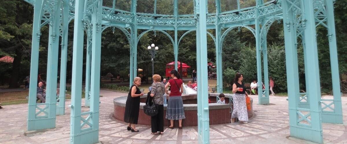 The Borjomi spring in Borjomi, Georgia.
This glass and steel pergola sits over two spigots of the famous Borjomi natural spring water.
Discovered thousands of years ago, but popularized during the Russian imperial period, the mineral waters of Borjomi became renowned for their healing qualities.
Russian figures such as Chekhov and Tchaikovsky visited Borjomi to relax in sanatoriums and drink the water.  During the Soviet period, bottled Borjomi water became one of the Soviet Union's chief exports.
If you travel to Borjomi, you can visit a central park and drink the warm water as it drips out of a spigot.  You travel to this area, descend some steps, and fill your cups or bottles with the water.
Entrance to the park is free before 9 AM - it costs fifty tetri the rest of the day.  Grabbing some water for the day is a good excuse for an early morning rise.