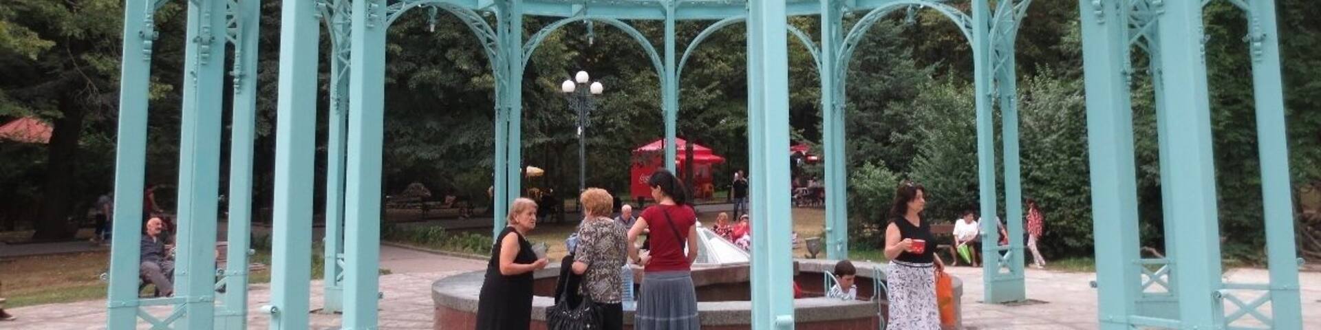 The Borjomi spring in Borjomi, Georgia.
This glass and steel pergola sits over two spigots of the famous Borjomi natural spring water.
Discovered thousands of years ago, but popularized during the Russian imperial period, the mineral waters of Borjomi became renowned for their healing qualities.
Russian figures such as Chekhov and Tchaikovsky visited Borjomi to relax in sanatoriums and drink the water. During the Soviet period, bottled Borjomi water became one of the Soviet Union's chief exports.
If you travel to Borjomi, you can visit a central park and drink the warm water as it drips out of a spigot. You travel to this area, descend some steps, and fill your cups or bottles with the water.
Entrance to the park is free before 9 AM - it costs fifty tetri the rest of the day. Grabbing some water for the day is a good excuse for an early morning rise.