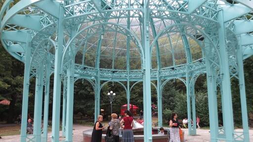 The Borjomi spring in Borjomi, Georgia.
This glass and steel pergola sits over two spigots of the famous Borjomi natural spring water.
Discovered thousands of years ago, but popularized during the Russian imperial period, the mineral waters of Borjomi became renowned for their healing qualities.
Russian figures such as Chekhov and Tchaikovsky visited Borjomi to relax in sanatoriums and drink the water. During the Soviet period, bottled Borjomi water became one of the Soviet Union's chief exports.
If you travel to Borjomi, you can visit a central park and drink the warm water as it drips out of a spigot. You travel to this area, descend some steps, and fill your cups or bottles with the water.
Entrance to the park is free before 9 AM - it costs fifty tetri the rest of the day. Grabbing some water for the day is a good excuse for an early morning rise.
