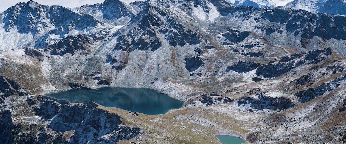 A mountainous landscape with a lake surrounded by snow-covered peaks.