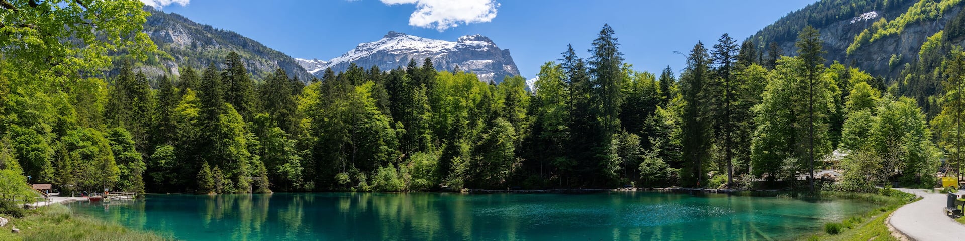 Panorama of the scenic mountain lake Blausee - Blue lake, located in the Kander valley above Kandergrund in the Jungfrau region, Switzerland.