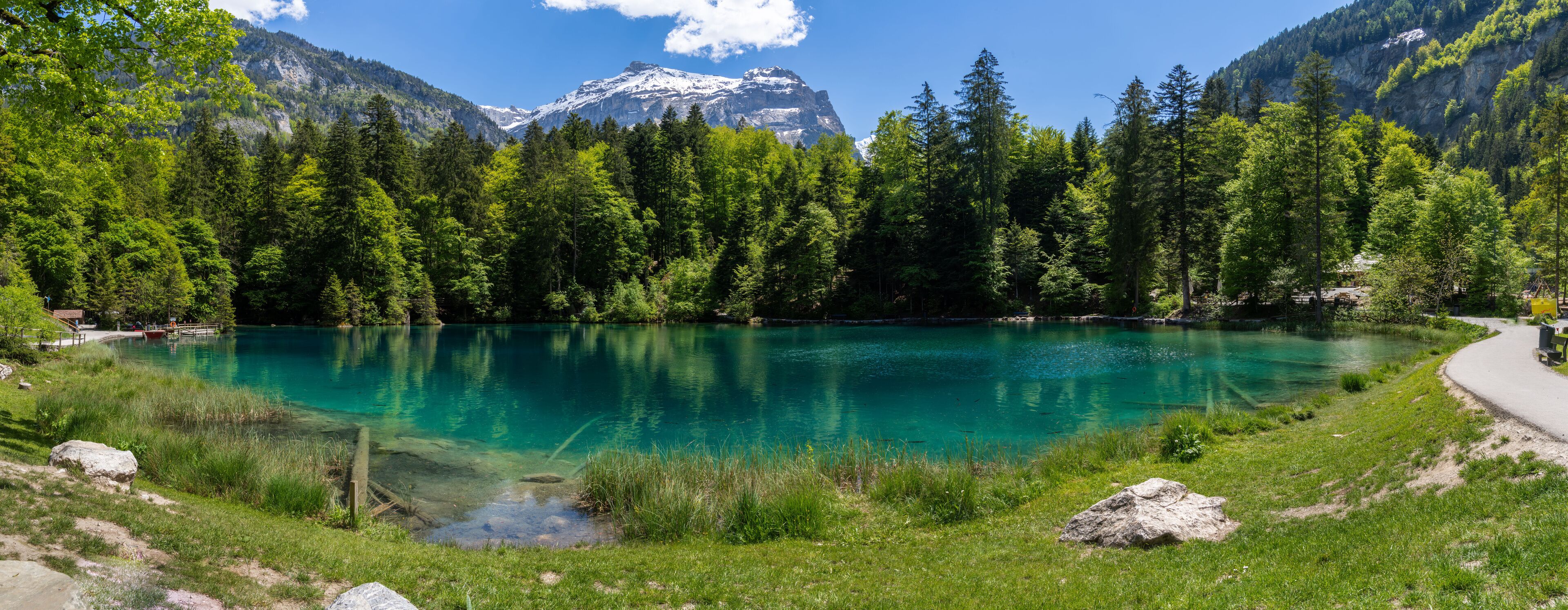 A clear lake surrounded by dense forest and mountains.