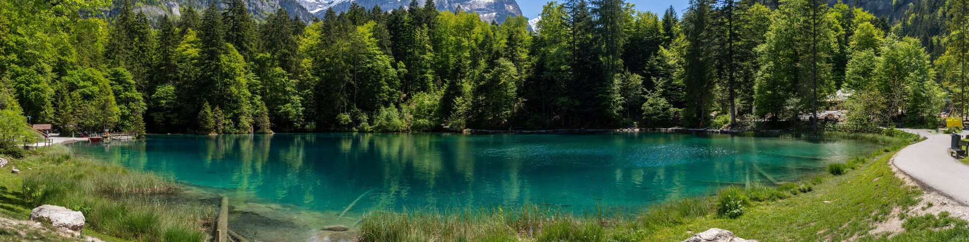 A clear lake surrounded by dense forest and mountains.