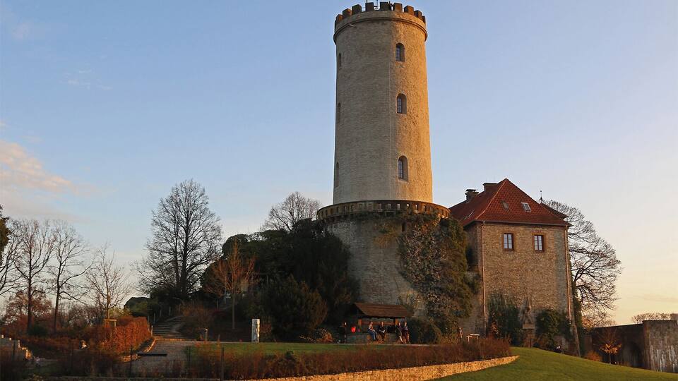A historic tower with a red-roofed building beside it.