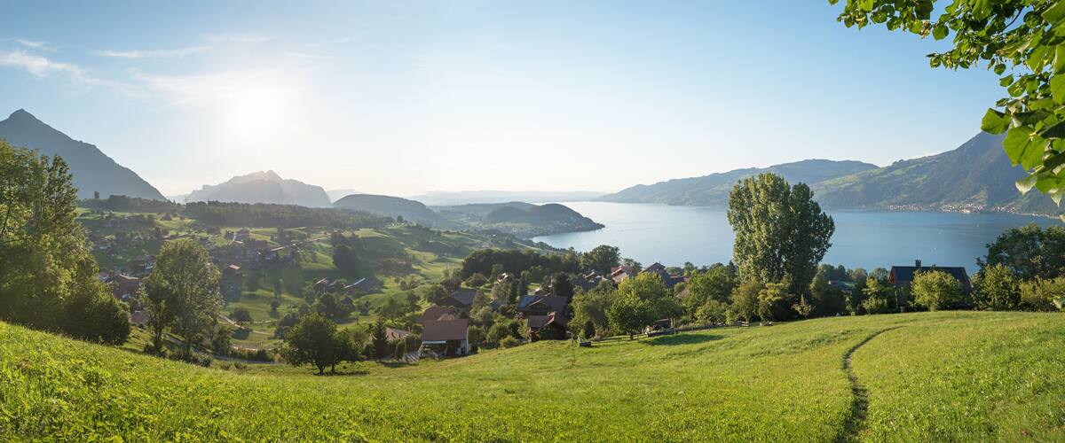 A mountainous landscape with a lake, green fields, and scattered houses.