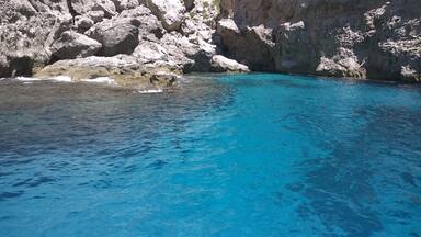 A clear blue sea with rocky cliffs.