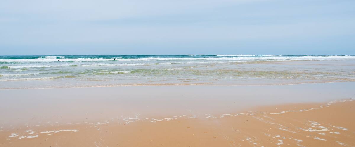 A beach with waves and a clear sky.