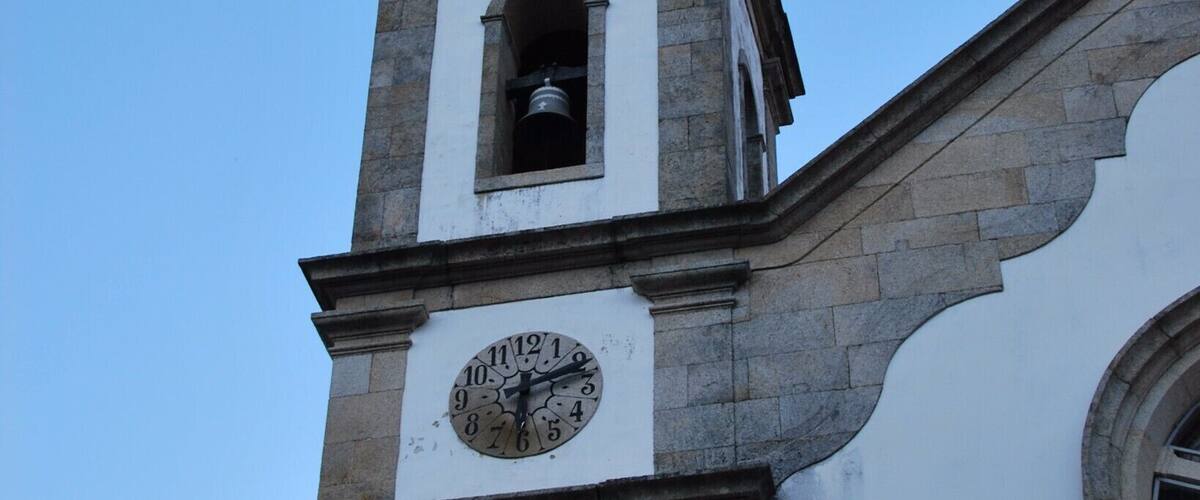 A church tower with a clock and a cross.