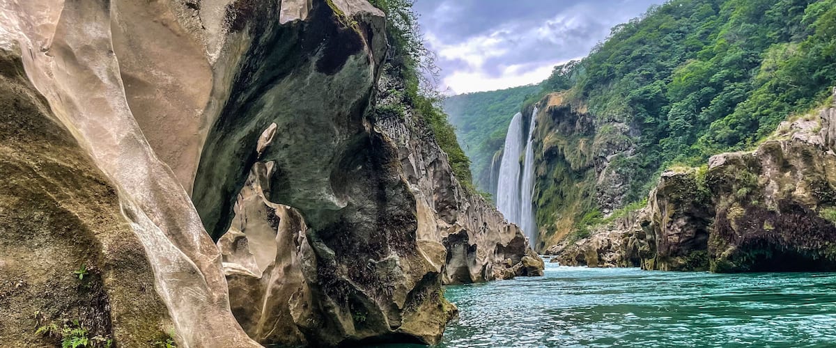 A river flowing through a rocky gorge with waterfalls and lush greenery.