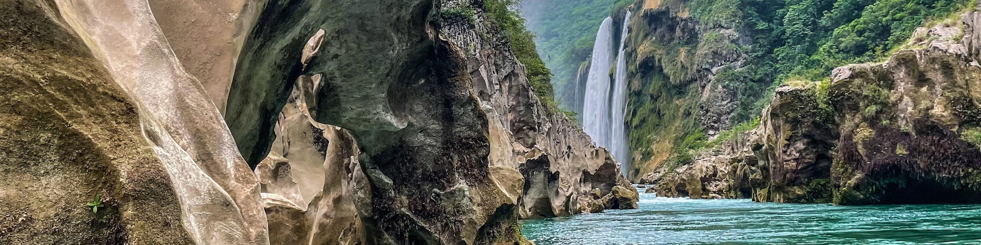 A river flowing through a rocky gorge with waterfalls and lush greenery.