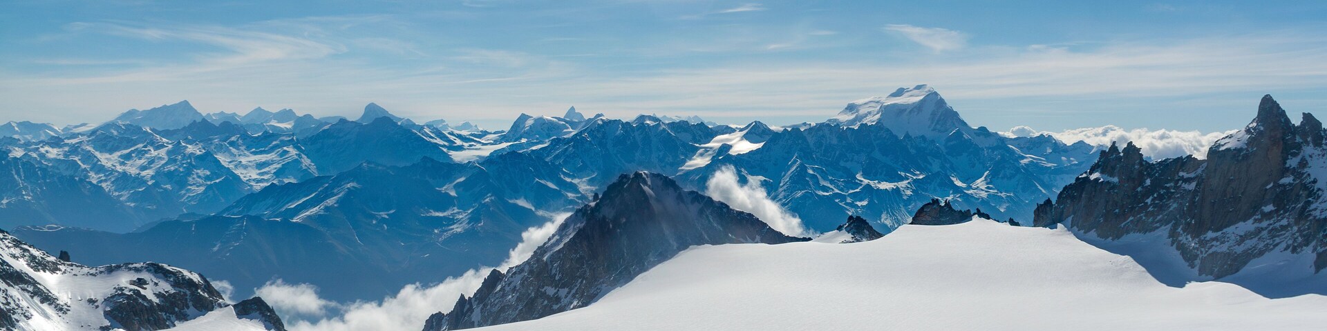Una cordillera nevada con picos escarpados y un cielo azul despejado.
