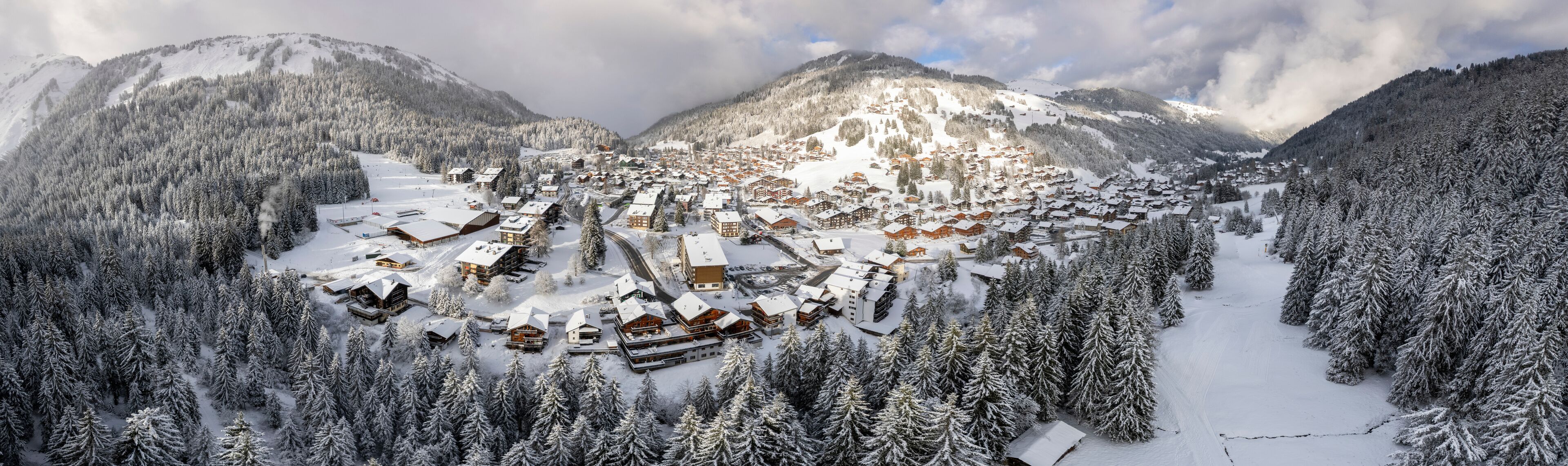 Aerial view of picturesque village surrounded by snow-covered mountains and frozen trees, Val-d'Illiez, Switzerland.