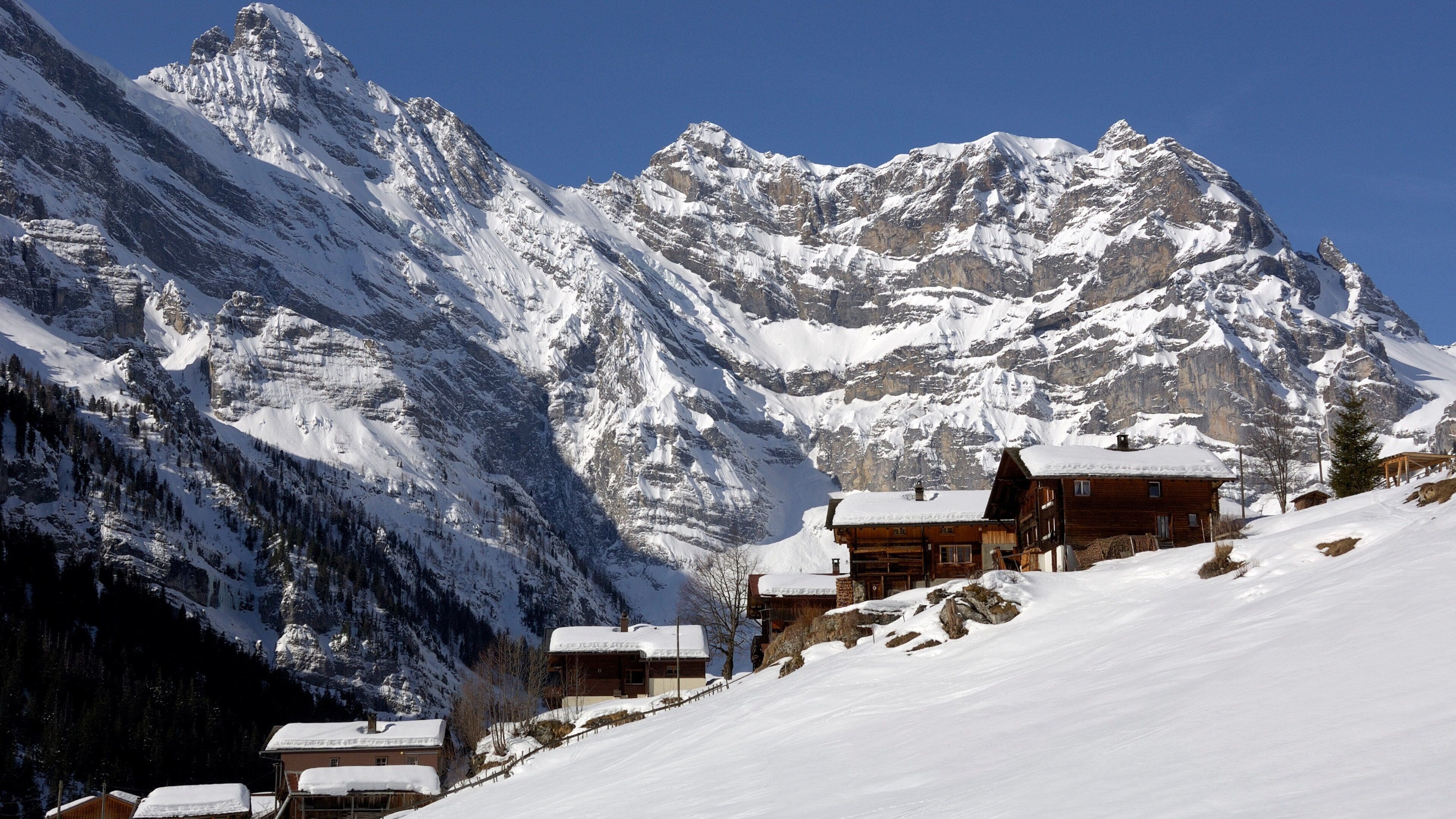 De bernesiske Alper som inkluderer liten by eller landsby, snø og fjell