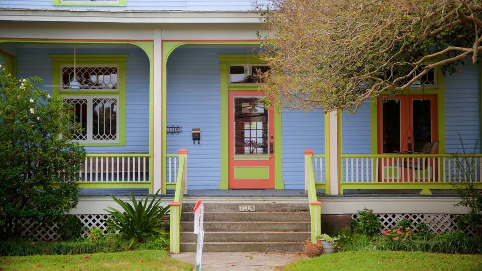 A colorful house with a porch, green railings, and a red door.