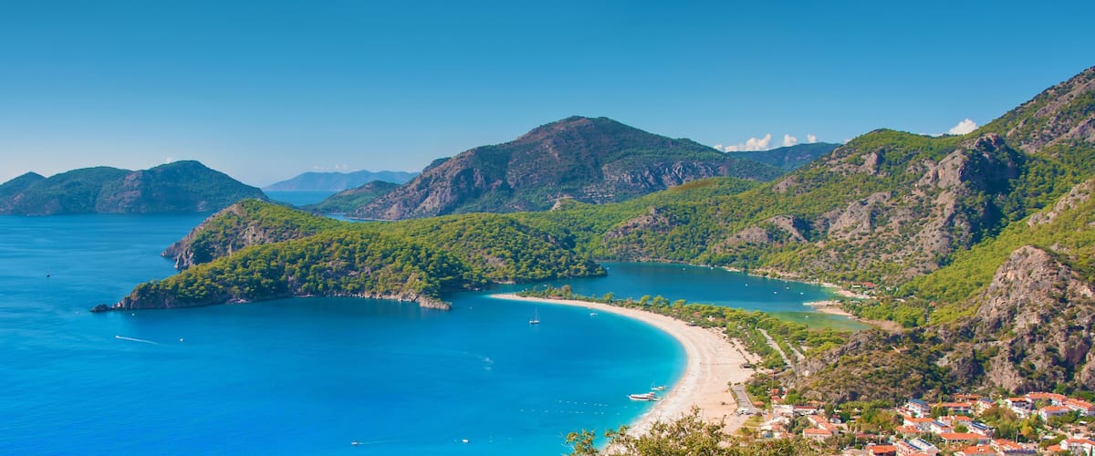 A coastal landscape with a bay, a beach, and a village.