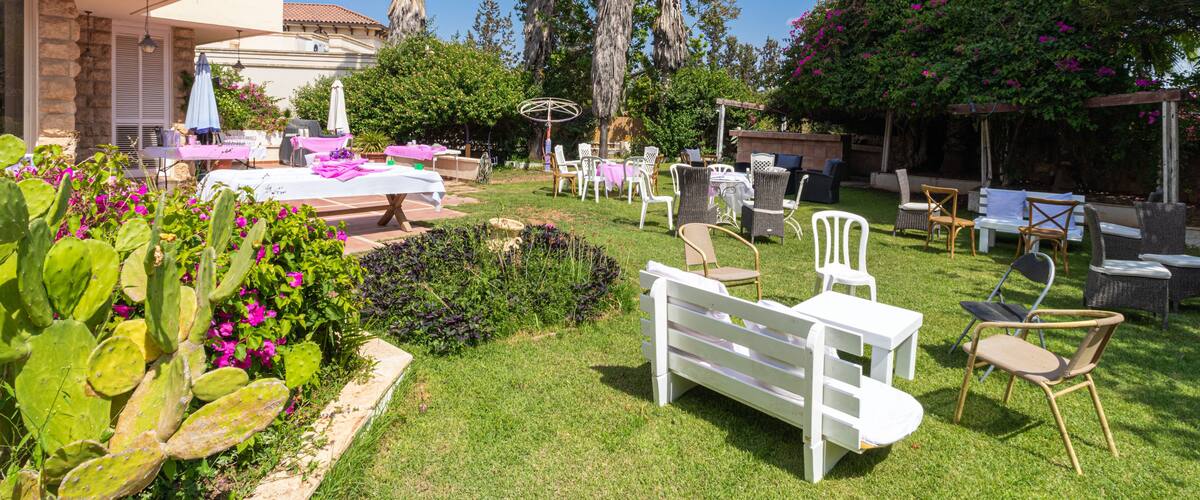 A well-maintained garden with palm trees, flowering plants, and outdoor furniture.