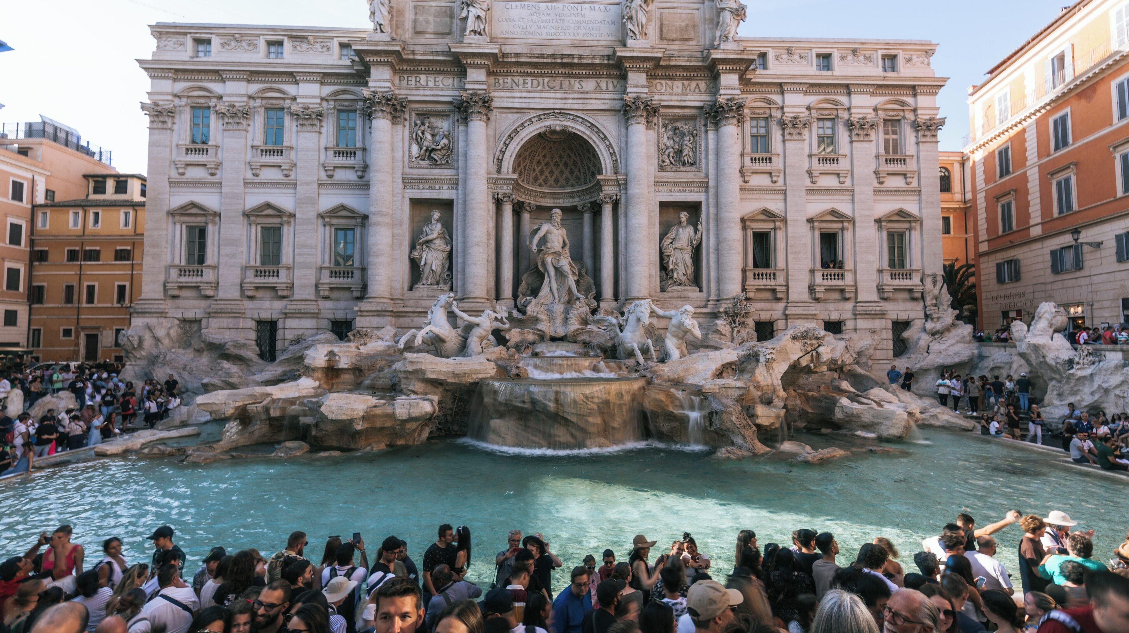 Visitors gather around Trevi Fountain in the historic center of Rome enjoying the architectural beauty and vibrant atmosphere of this iconic landmark