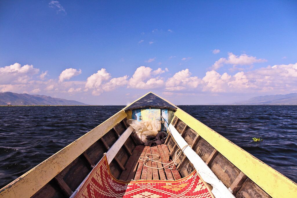 A wooden boat on a calm body of water with mountains in the background.