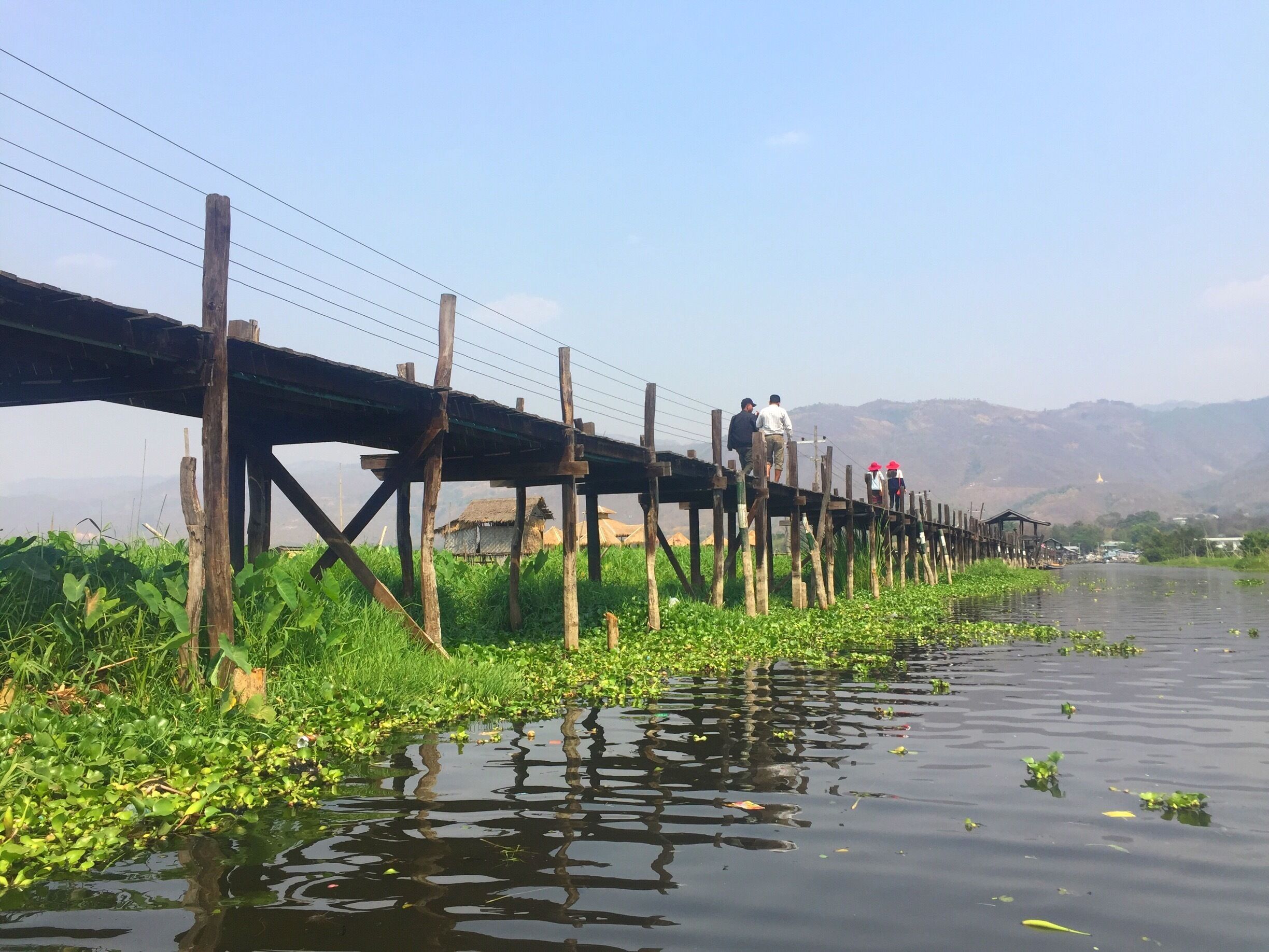 A wooden bridge over a river with vegetation on the banks.