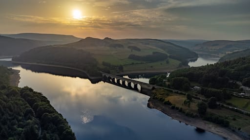 A river with a bridge, surrounded by hills and fields.