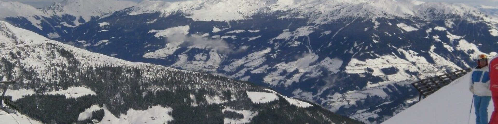 Paisaje nevado de montaña con remontes y esquiadores.